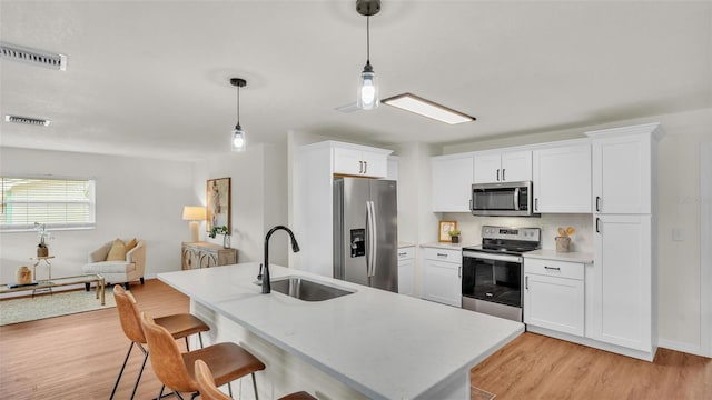 kitchen with a breakfast bar, stainless steel appliances, light countertops, visible vents, and a sink