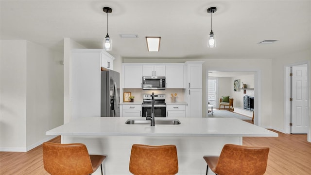 kitchen with appliances with stainless steel finishes, a breakfast bar, and white cabinetry