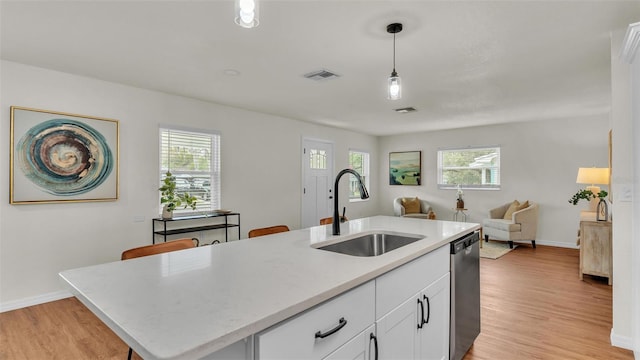 kitchen with dishwasher, light wood finished floors, open floor plan, and a sink