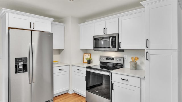 kitchen featuring white cabinets, light wood-style flooring, appliances with stainless steel finishes, and light countertops