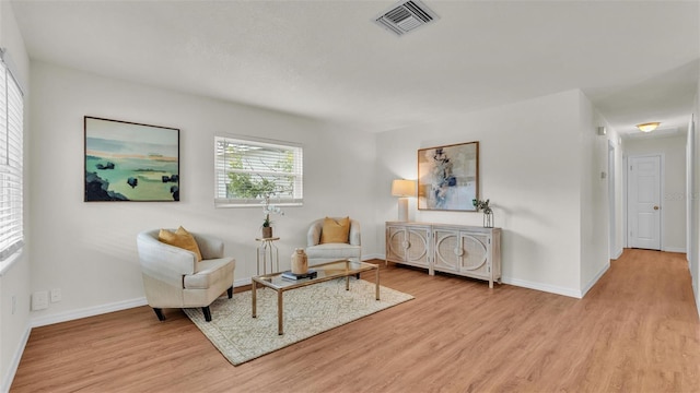 living area featuring baseboards, visible vents, and wood finished floors