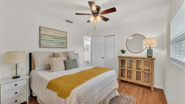 bedroom with a closet, visible vents, a ceiling fan, wood finished floors, and baseboards