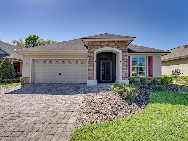 view of front of home with stucco siding, decorative driveway, stone siding, a front yard, and a garage