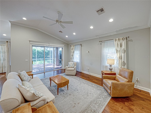 living area featuring vaulted ceiling, wood finished floors, visible vents, and ornamental molding