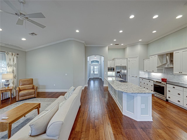 kitchen with tasteful backsplash, visible vents, arched walkways, stainless steel appliances, and wall chimney exhaust hood