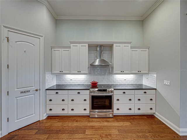 kitchen with dark countertops, wall chimney exhaust hood, stainless steel electric stove, and light wood-style flooring