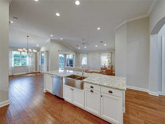 kitchen with wood finished floors, arched walkways, a sink, dishwasher, and open floor plan