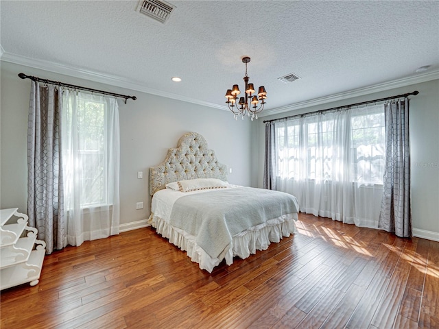 bedroom with visible vents, a notable chandelier, hardwood / wood-style floors, and crown molding