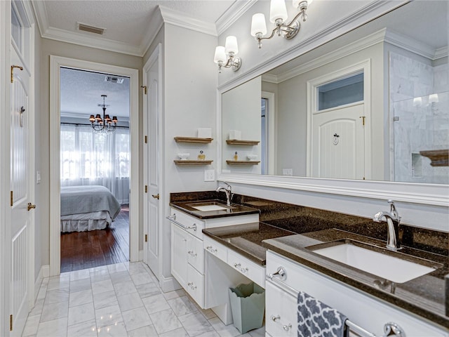 ensuite bathroom with a sink, visible vents, a textured ceiling, and an inviting chandelier