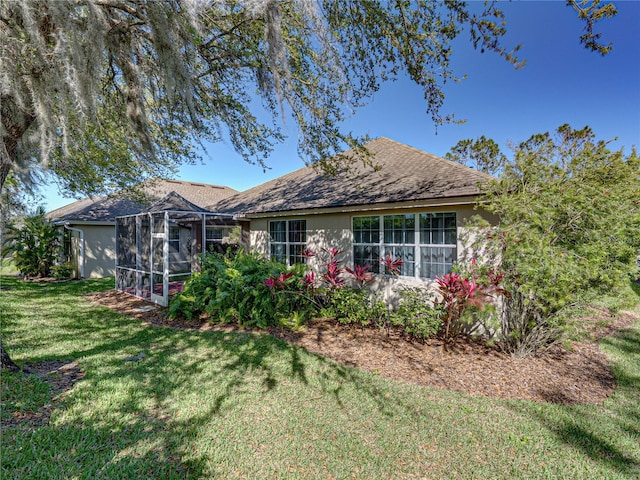 back of property with a lanai, stucco siding, and a yard