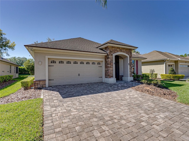 view of front of house with decorative driveway, stone siding, and an attached garage