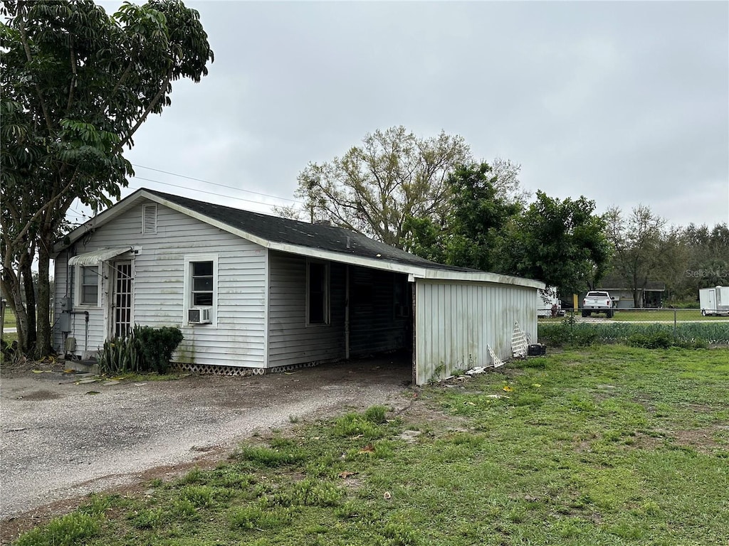 view of outbuilding featuring an attached carport, cooling unit, and driveway