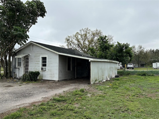 view of outbuilding featuring an attached carport, cooling unit, and driveway