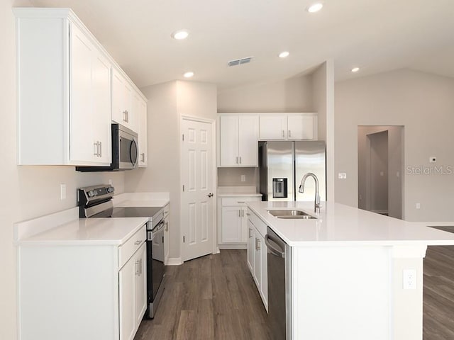 kitchen featuring dark wood finished floors, appliances with stainless steel finishes, white cabinets, vaulted ceiling, and a sink