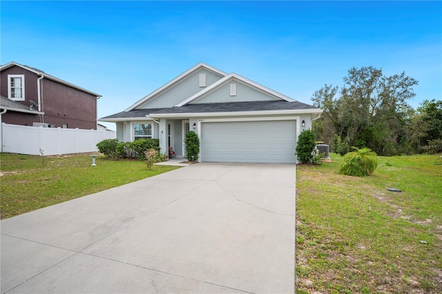 view of front of home with driveway, an attached garage, fence, cooling unit, and a front lawn