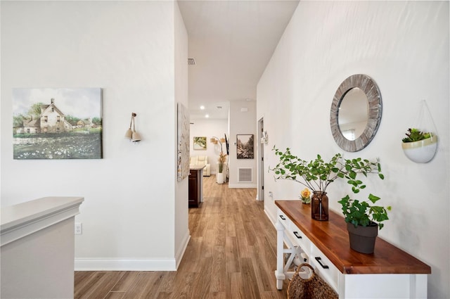 hall with light wood-style floors, visible vents, and baseboards