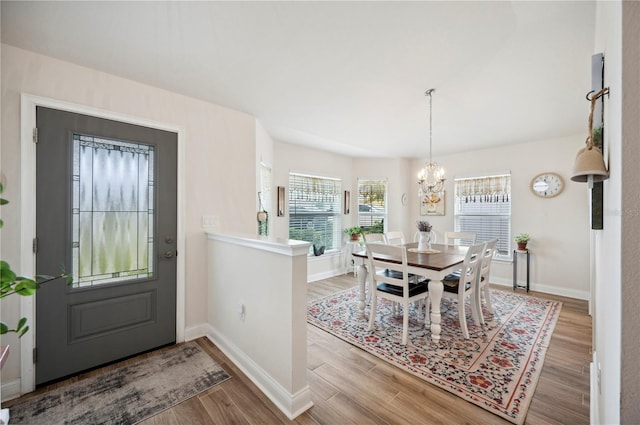 dining room with a chandelier, wood finished floors, and baseboards