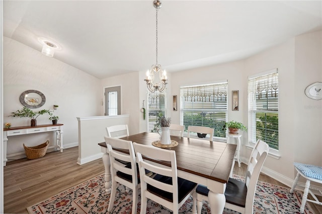 dining space featuring an inviting chandelier, baseboards, and wood finished floors