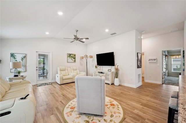 living area with light wood-type flooring, a wealth of natural light, visible vents, and vaulted ceiling