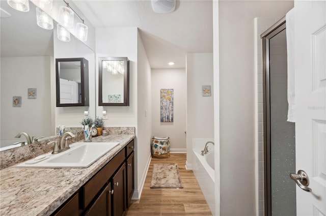 bathroom with vanity, wood finished floors, a bath, and baseboards