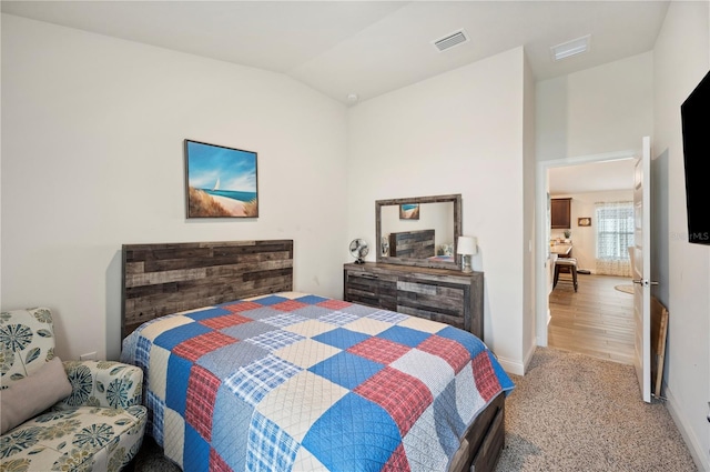 carpeted bedroom featuring lofted ceiling, visible vents, and baseboards