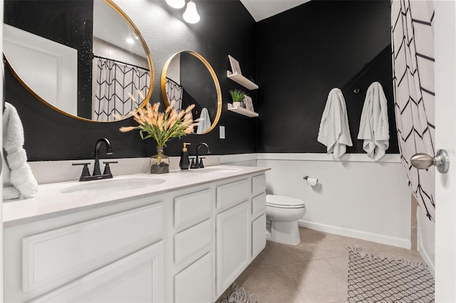 bathroom with double vanity, tile patterned flooring, a sink, and toilet