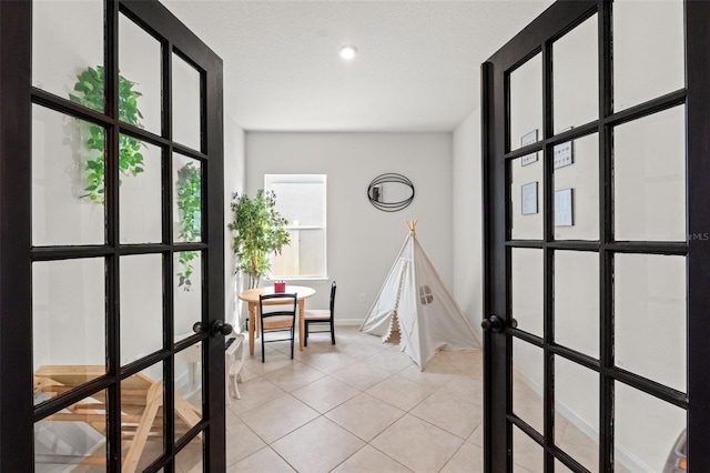 interior space with french doors, light tile patterned flooring, and baseboards