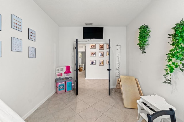 recreation room with light tile patterned floors, visible vents, and baseboards