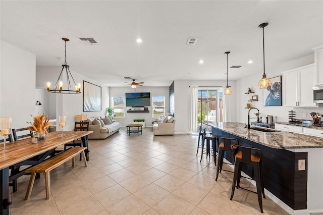 kitchen with light tile patterned floors, a sink, visible vents, and light stone countertops