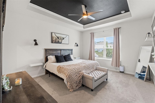 bedroom featuring baseboards, a tray ceiling, and light colored carpet