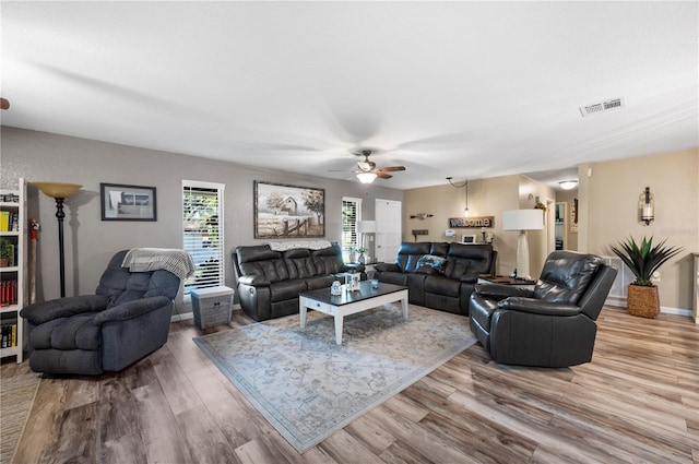 living area with visible vents, ceiling fan, baseboards, and wood finished floors