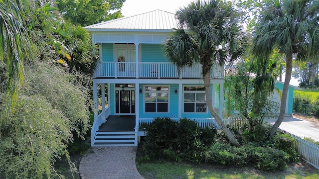 view of front of house with covered porch, fence, a balcony, and metal roof