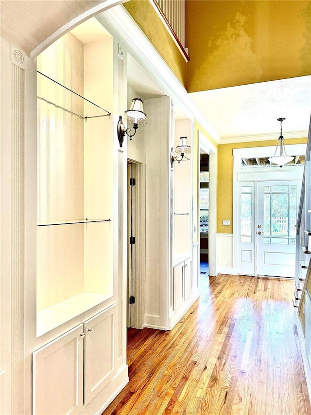 entryway featuring a wainscoted wall, light wood finished floors, plenty of natural light, and crown molding