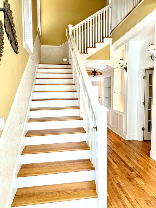 stairs featuring a high ceiling and wood finished floors