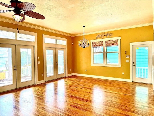 interior space with a textured ceiling, baseboards, light wood-style floors, french doors, and crown molding