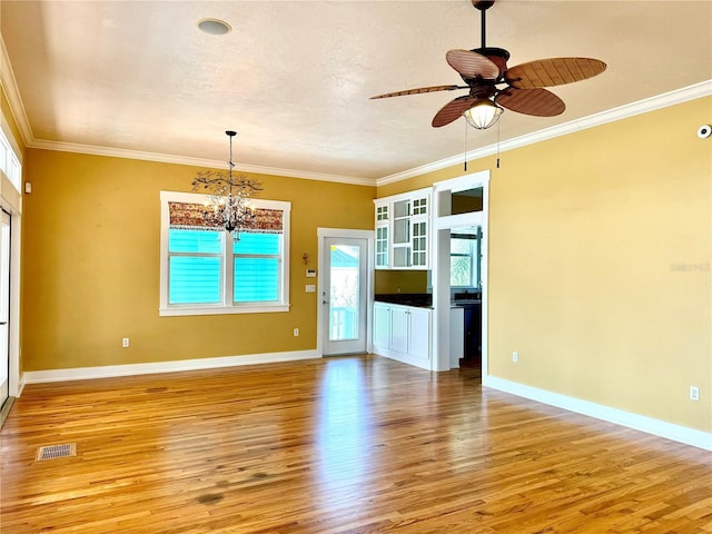 spare room featuring crown molding, ceiling fan with notable chandelier, baseboards, and light wood-style floors