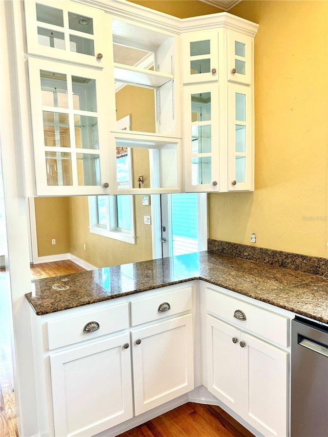 kitchen featuring dark stone countertops, white cabinets, glass insert cabinets, and stainless steel dishwasher