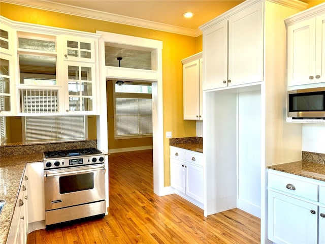 kitchen featuring dark stone countertops, appliances with stainless steel finishes, white cabinets, and crown molding