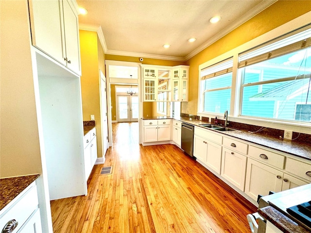 kitchen featuring crown molding, dark countertops, light wood-style flooring, stainless steel dishwasher, and a sink