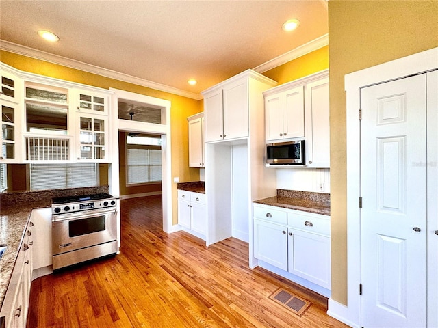 kitchen featuring stainless steel appliances, white cabinets, visible vents, and light wood-style flooring