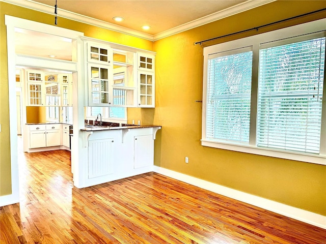 kitchen with plenty of natural light, light wood-style flooring, white cabinets, and crown molding