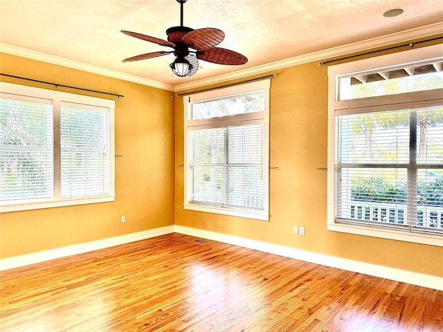 empty room featuring a ceiling fan, crown molding, baseboards, and wood finished floors