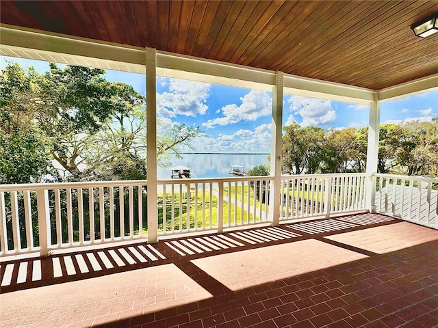 unfurnished sunroom featuring a water view, a healthy amount of sunlight, and wooden ceiling