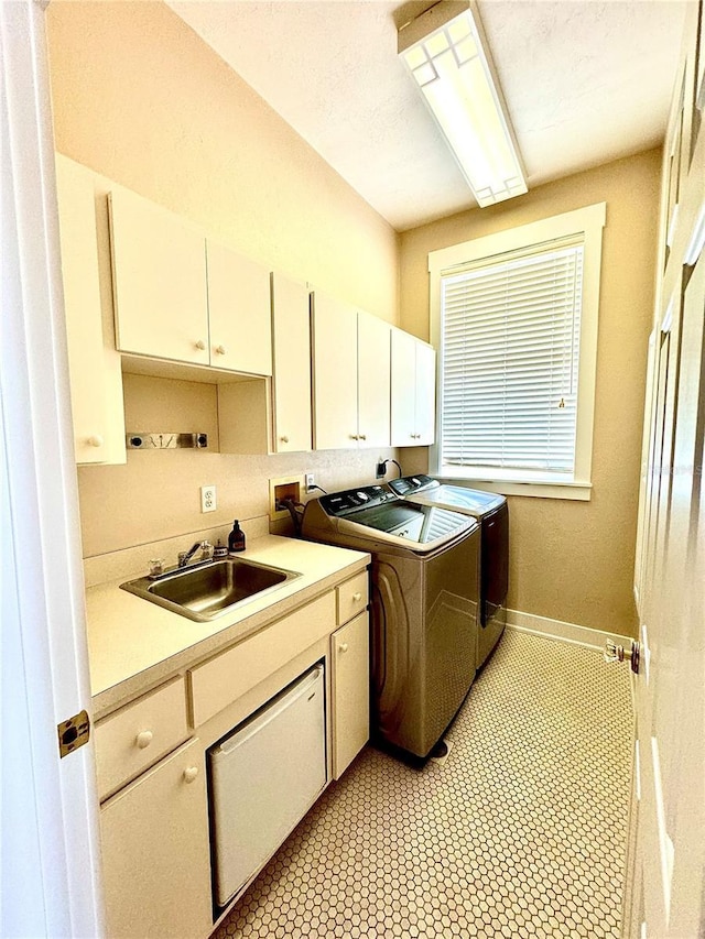 clothes washing area featuring washing machine and clothes dryer, a sink, cabinet space, and baseboards