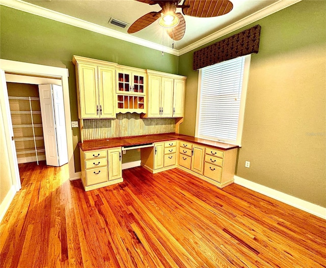 unfurnished office featuring built in study area, crown molding, visible vents, and light wood finished floors