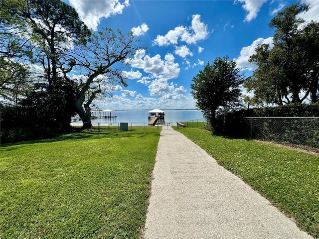 exterior space featuring a water view, a boat dock, and fence