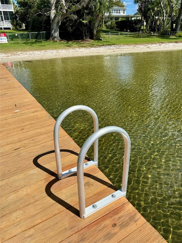 view of dock with a water view and fence