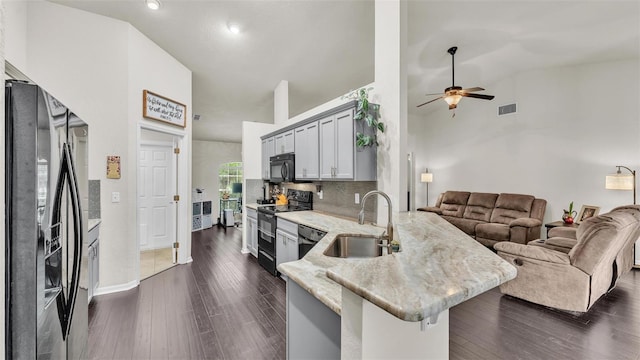 kitchen with visible vents, dark wood-type flooring, a peninsula, black appliances, and a sink