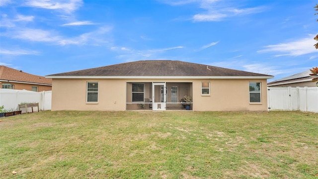 rear view of house featuring a fenced backyard, a lawn, and stucco siding