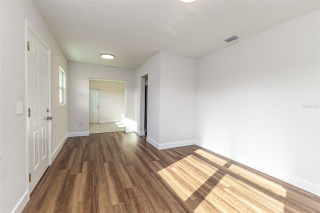 unfurnished room with baseboards, visible vents, and wood finished floors